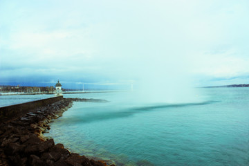 Fototapeta premium Swiss famous view in Geneva with popular fountain, lake and lighthouse on rainy spring day