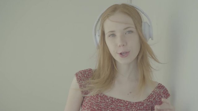 Beautiful red-haired woman with headphones listen to music, color profile Slog3