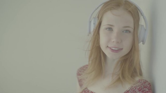 Beautiful red-haired woman with headphones listen to music, color profile Slog3