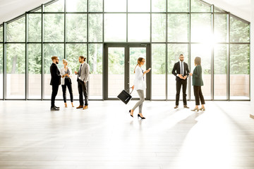 Fototapeta premium Business people at the spacious modern hall with big window overlooking on the park. Wide view with copy space