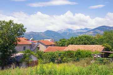 Obraz premium Summer landscape. Buildings with red roofs among mountains and green trees. Montenegro, Tivat