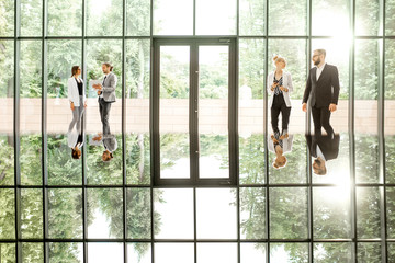 Fototapeta na wymiar Business people at the modern office hall with window on the background overlooking on the park. View directly with reflection from the table