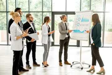 A group of business people standing together during the conference with flip chart at the modern office