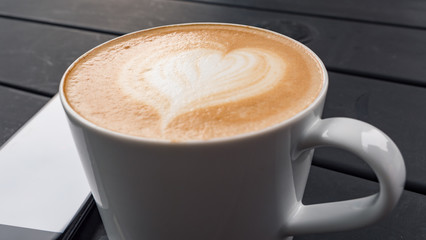 technology, business and modern life concept- close up of smartphone and coffee cup on table at cafe