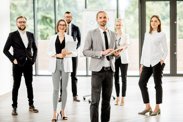 Portrait of a group of business people standing during a conference with flip chart at the modern office