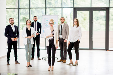Portrait of a group of business people standing during a conference with flip chart at the modern office