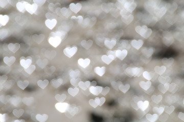 White bokeh Heart-shaped lights reflecting on the wet muddy ground. White silver bokeh background...