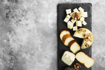 Various types of cheese on a gray background. Top view, copy space. Food background