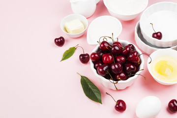 Ingredients for cherry pie - milk, butter, eggs, flour, cherry, sugar on a pink background. Copy space. Food background