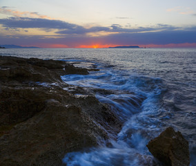 Naklejka na ściany i meble Beautiful cloudscape over the sea, sunrise shot. Waves among the rocks, rocks on horizon. Crete, Greece