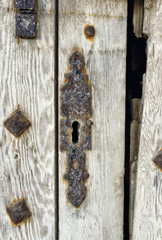Key hole over aged gray old wood, rusty metal