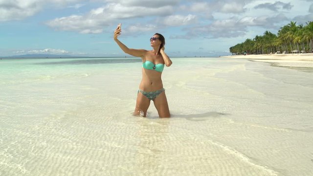 A woman in a swimsuit makes a selfie on the seashore