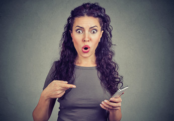 woman looking with terrified expression at camera pointing at smart phone