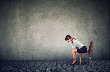 Depressed business woman sitting on chair and looking down