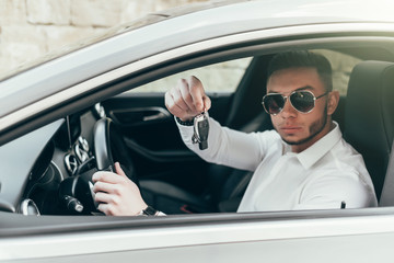 Handsome Young Man Showing Car Keys in His Newly Bought Auto Sitting in the Luxury Vehicle