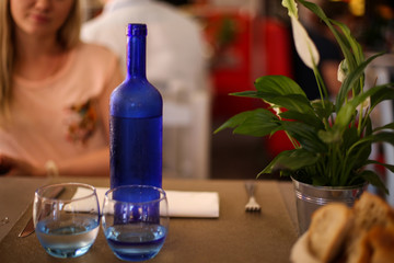 Cold fresh water in blue bottle with glasses on a cafe table