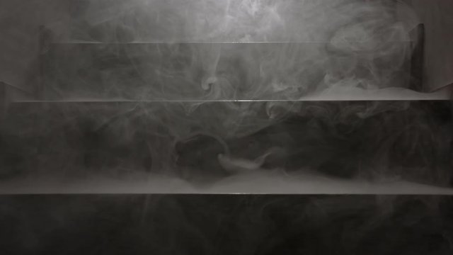 Medium shot of foggy smoke hanging on darkened staircase back lit