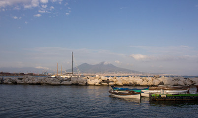 Fototapeta premium Sailboats in dock against Vesuvius volcano and Mediterranean sea. Boats in harbour in Naples (Napoli), Italy. Sailing and travel concept. Calm evening on seashore. Neapolitan landmark. 