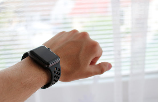 Man's hand with black smart watch in office