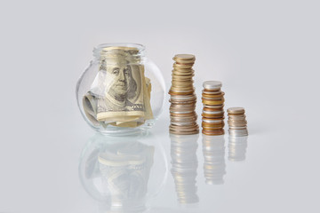 Packs of coins and dollar bills in a glass bottle on a glass table. Business concept