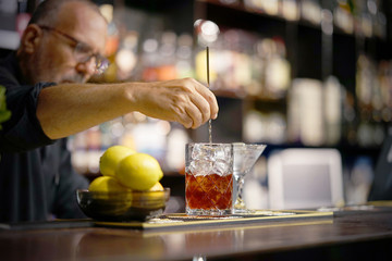 A bartender stirring ingredients in a mixing glass in order to prepare and serve a chilled cocktail...