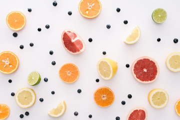 top view of citrus fruits slices and blueberries on white surface