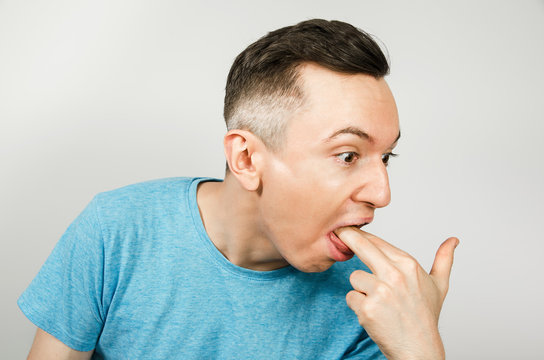 Young Guy Inserts Two Fingers In The Mouth To Induce Vomiting, On A Light Background.