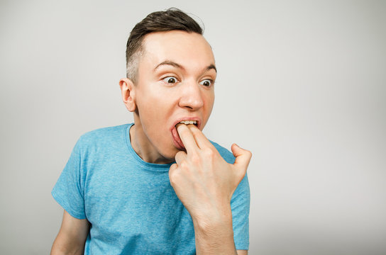 Young Guy Inserts Two Fingers In The Mouth To Induce Vomiting, On A Light Background.