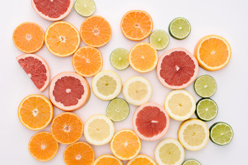 top view of various citrus fruits slices spilled on white surface