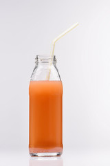 glass bottle of fresh grapefruit juice on white