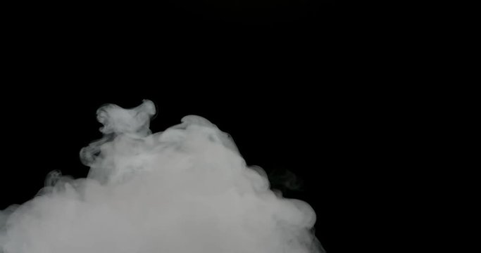 Smoke cloud boiling up from bottom of frame dissipating into black