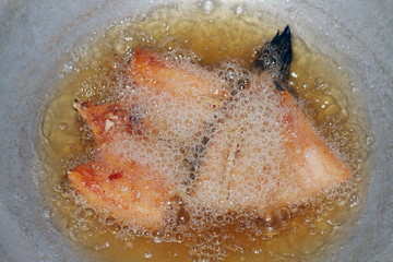 Fototapeta premium Fried fish pieces in hot oil pan, Fried fish for diet, Fish cutting Portion slice fried in oil cooking pan is food protein diet health