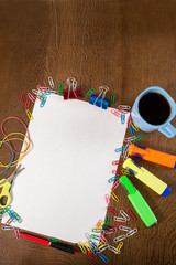 Fototapeta premium A blank white paper with cup of coffee and different office tools on the table