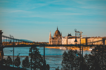 Fototapeta na wymiar danube river with chain bridge and parliament and some silhouettes of trees in the foreground