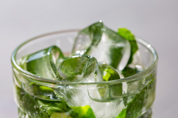 Twigs green mint in mojito with slices lime, ice cubes, straw, macro, texture