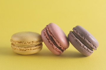 Three Varieties of French Macarons on a Yellow Background