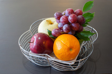 Fresh fruit in basket with black wood background