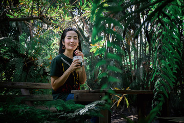 Lady fefreshing drink iced coffee on the table in the forest green