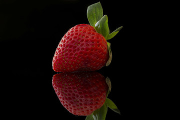 close up front big strawberry with reflection and black background