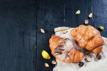 Tasty croissants with chocolate on black wooden background