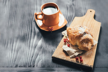 sweet croissants and cup of coffee on black wooden background. Copy space