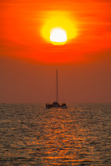 Naklejka na ściany i meble A Boat is floating on the sea under big sunset time at Tropicana located at south of Thailand