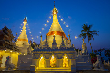 Fototapeta premium A white color of pagoda decorated by lighting at night time under clear sky located at north of Thailand