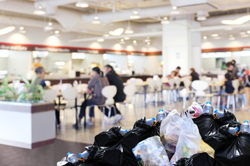 plastic waste garbage bag black bin full Lots pile of junk at front canteen food court mall department store background, pollution garbage bin pile dump trash waste