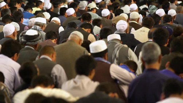A group of Islamic people giving grace inside a mosque.