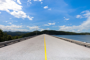 Road through yellow lanes with clouds on blue sky in winter