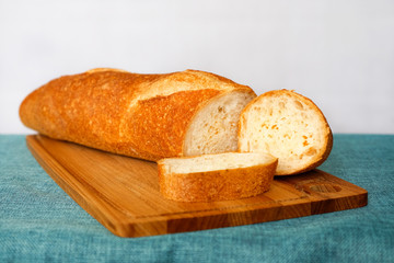 White wheat bread, fresh bread on the table in the dark interior. With the brain bread cut into place on the cutting Board. Crisp and fresh. Enjoy your meal.