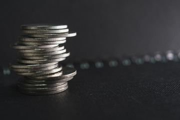 a stack of silver coins on a dark surface.