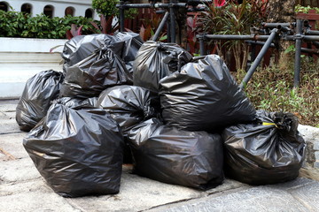 waste lots pile of garbage black bags plastic stack on the floor ground public park, many dump black garbage plastic bags stack