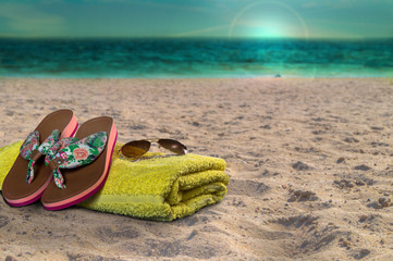 Handtuch, Flip Flops und Sonnenbrille am Strand. Sonnenuntergang am Abend.